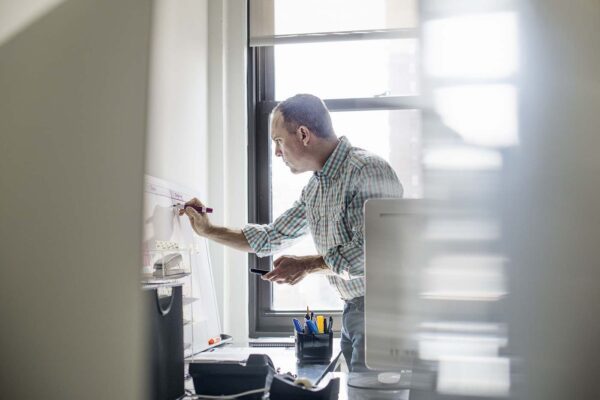 Office,Life.,A,Man,Standing,Up,Working,And,Making,Notes