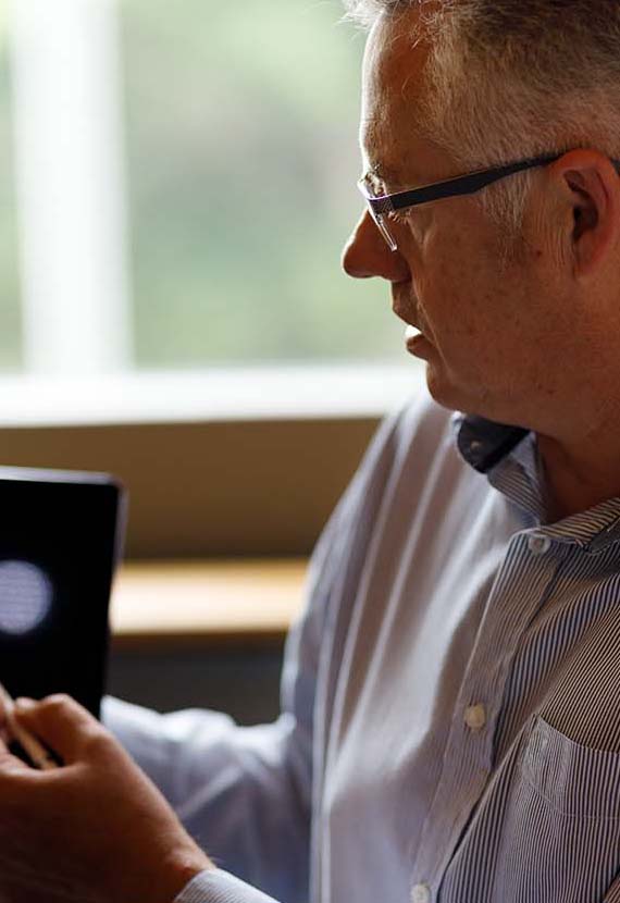 Mature,Caucasian,Businessman,Presenting,Information,On,Digital,Tablet,To,Team